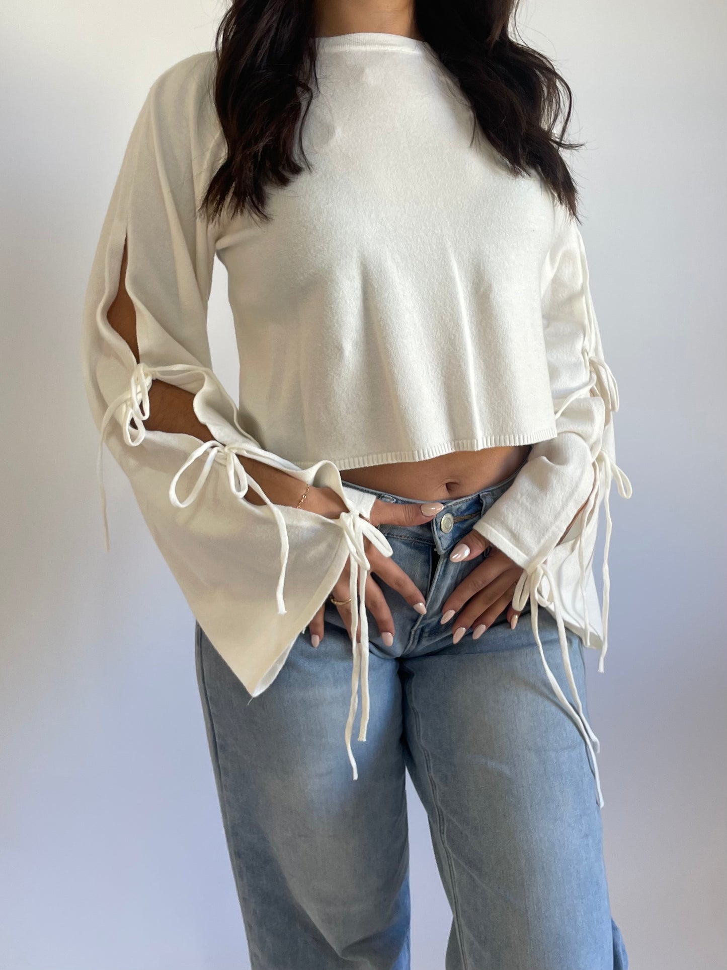 Soft knitted wide long sleeve blouse. Ties into bows at the sleeves and is slightly cropped. Available in black and white.
